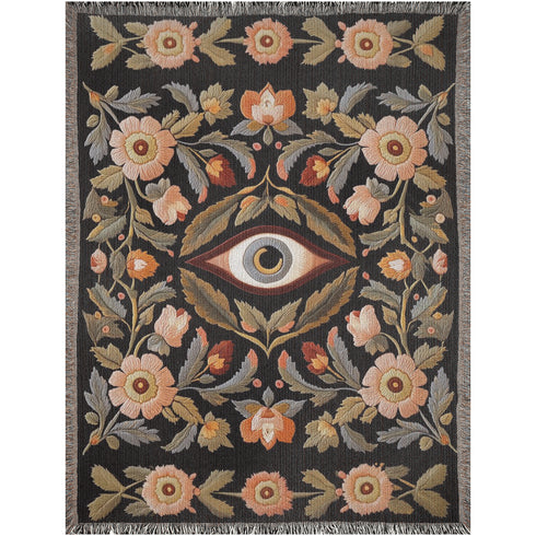 A luxury woven jacquard blanket in three sizes featuring an all-over wild herb botanical pattern of stylized blossoms and foliage in muted gold, olive, lavender, and pewter on a deep black cotton ground; finely twisted multicolor fringe edges complete the artful tapestry weave, ideal as a cozy sofa throw or dramatic wall hanging.